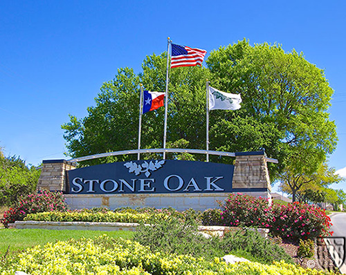 Stone Oak entrance monument with flags and landscaped gardens